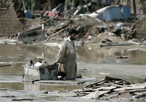 ap_pakistan_floods_480_14Aug10 A flood survivor wades through mud as he salvages belongings in Azakhel, near Nowshera, northwest Pakistan, 14 Aug 2010